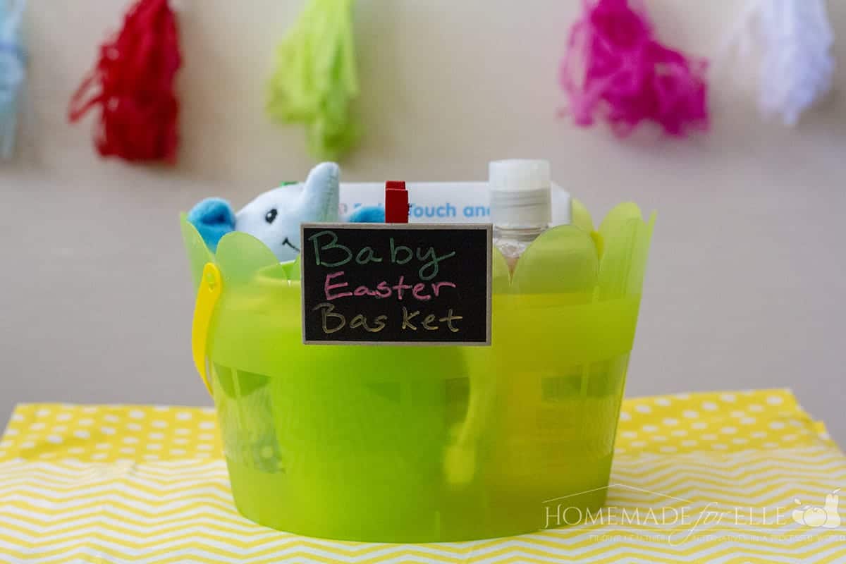 green bucket holding toys like blue stuffed elephant with tag Baby Easter Basket.