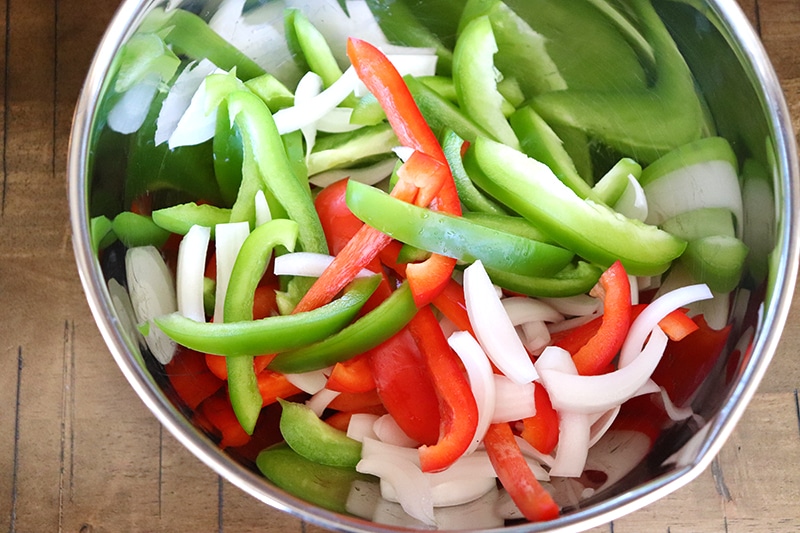 A bowl of diced green bell peppers, red bell peppers, and onions