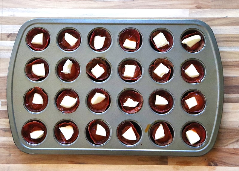 Pepperoni pizza bites in mini muffin pans before going in the oven 