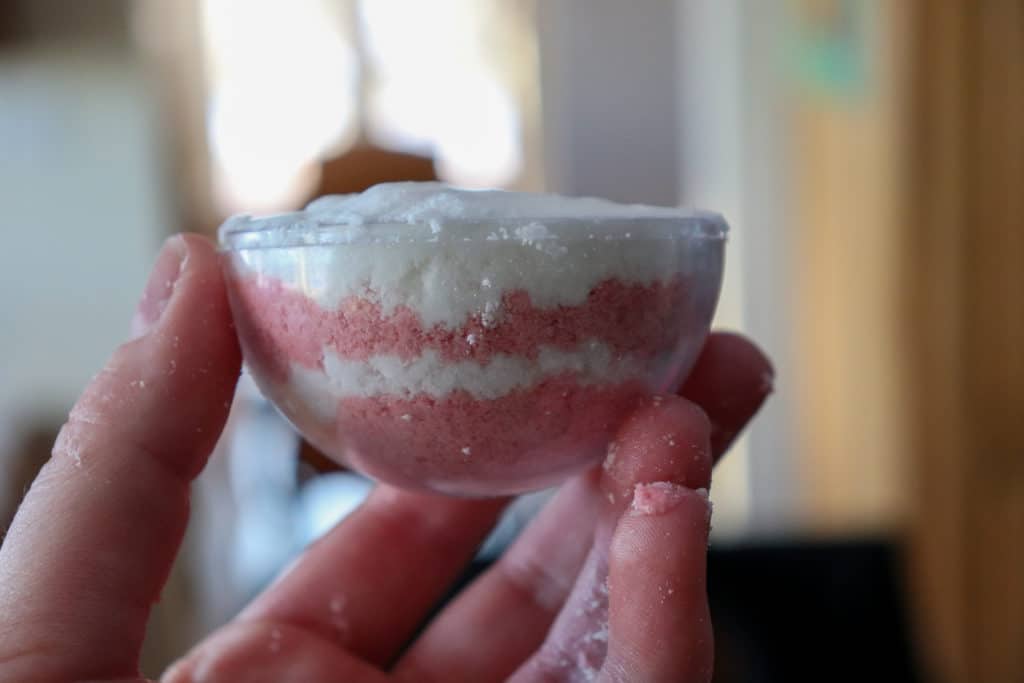 layering red and white bath bomb mixture for candy cane bath bomb recipe